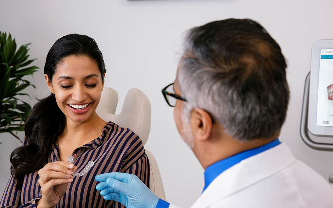 Woman holding Invisalign aligner with doctor