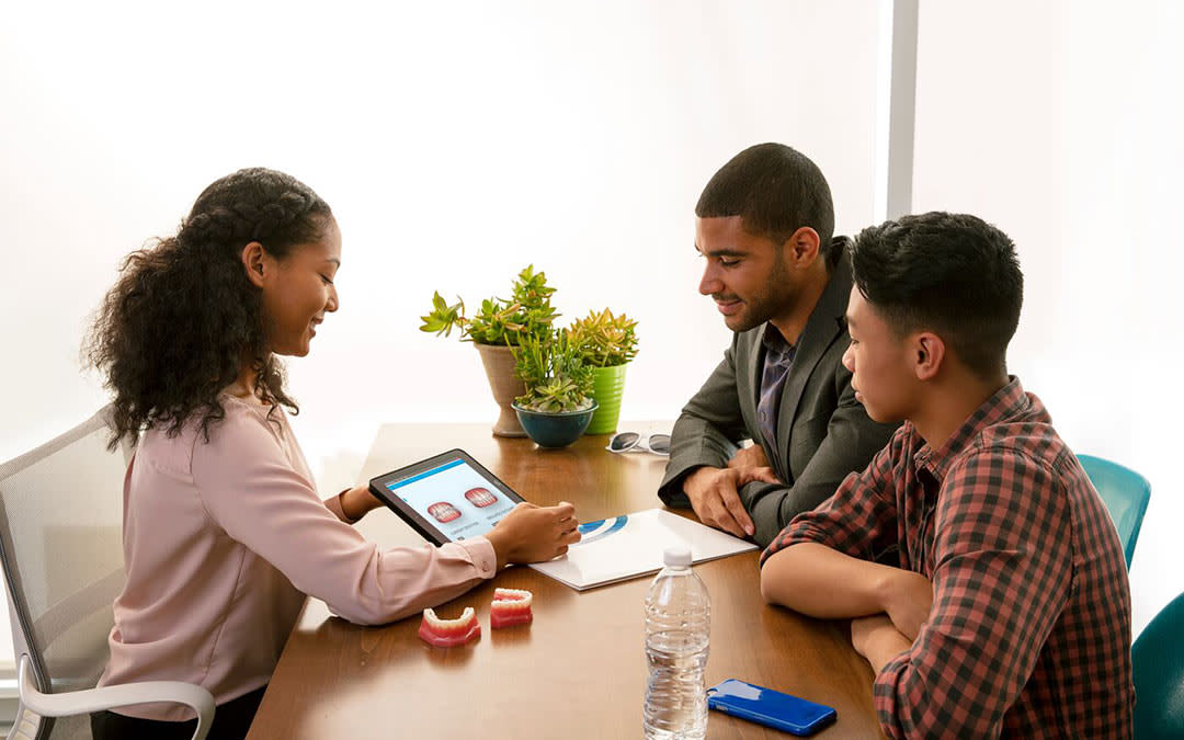 Doctor reviewing teeth scan with man and boy
